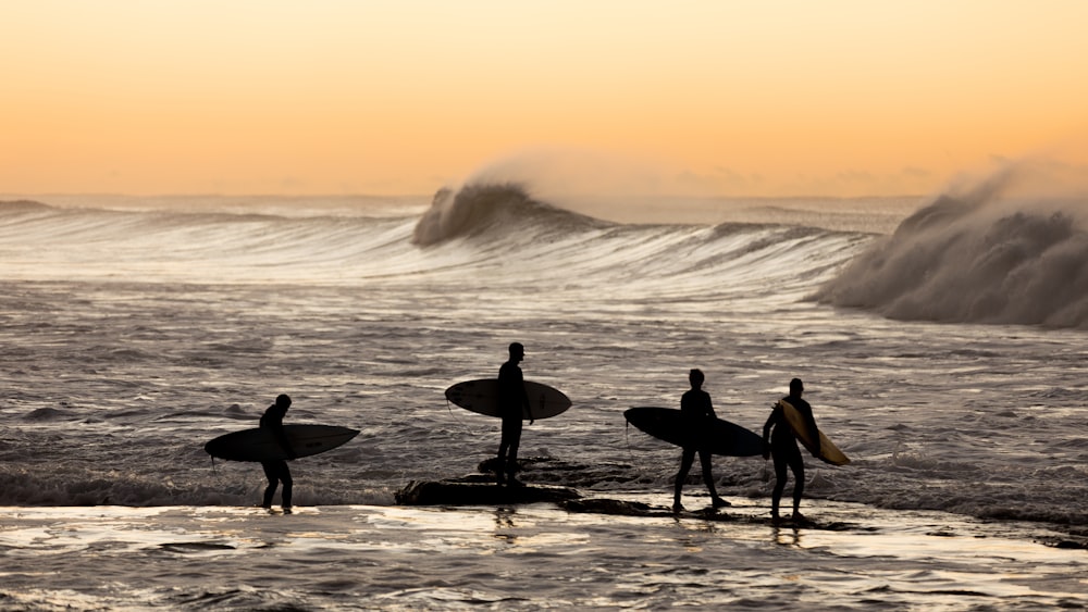 a group of surfers walking on the beach
