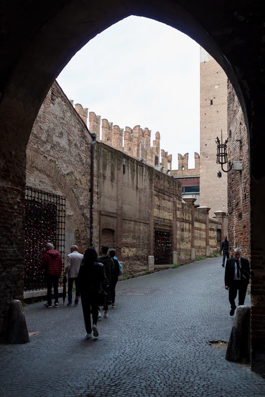 people walking under a stone archway