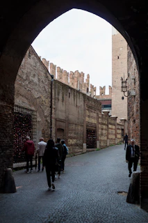 people walking under a stone archway