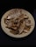A plate filled with several dried fish, arranged in a somewhat haphazard manner. The fish have a distinctly brown and desiccated appearance, indicating they have been preserved.