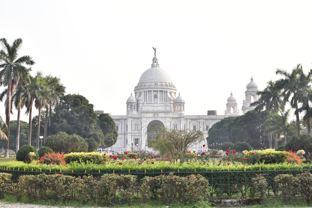 a large white building with a dome and many trees in front of it with Victoria Memorial Hall in the background