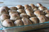 Freshly baked rolls with a shiny glaze, stacked invitingly on a woven bamboo tray.