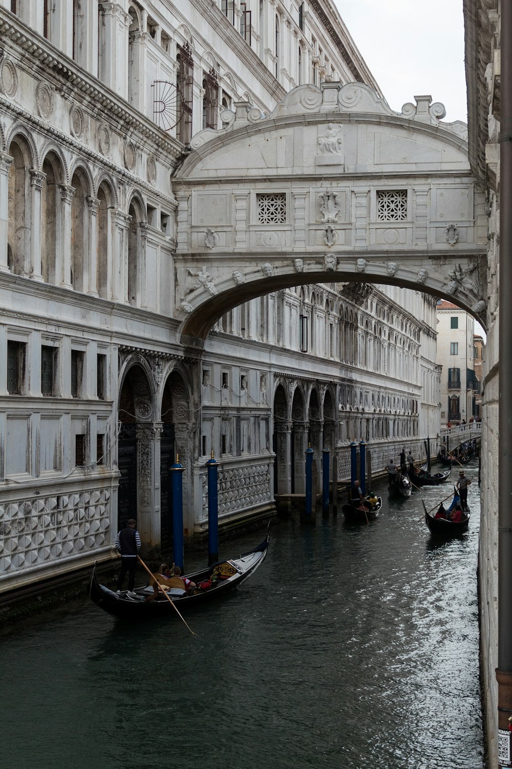 a group of boats in a canal with Bridge of Sighs in the background
