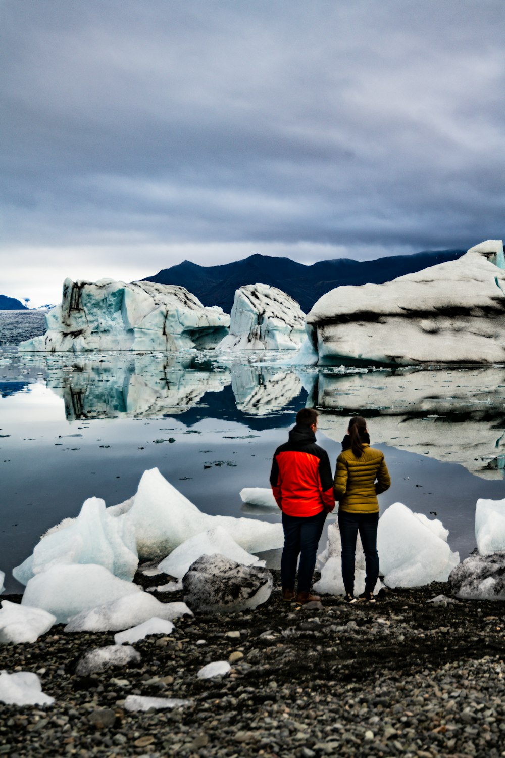 a man and woman standing in front of a glacier