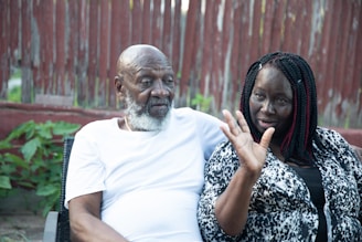 Smiling elderly couple enjoying a conversation outdoors with hearing aids visible