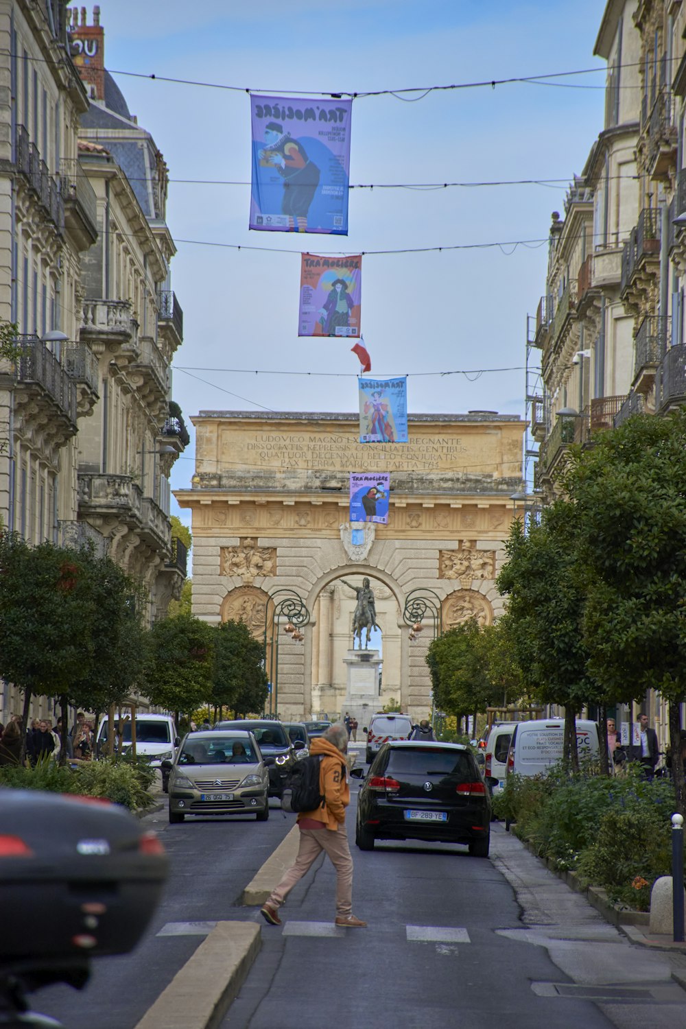 a person walking down a street with cars and buildings on either side