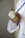 A person wearing a white coat is holding a stethoscope in their hand. The person's nails are painted a bright green color. The focus is on the stethoscope, while the background is blurred.