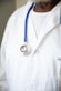 A person wearing a white lab coat with a blue stethoscope draped around their neck. The focus is on the upper body, highlighting the medical attire typically associated with healthcare professionals.
