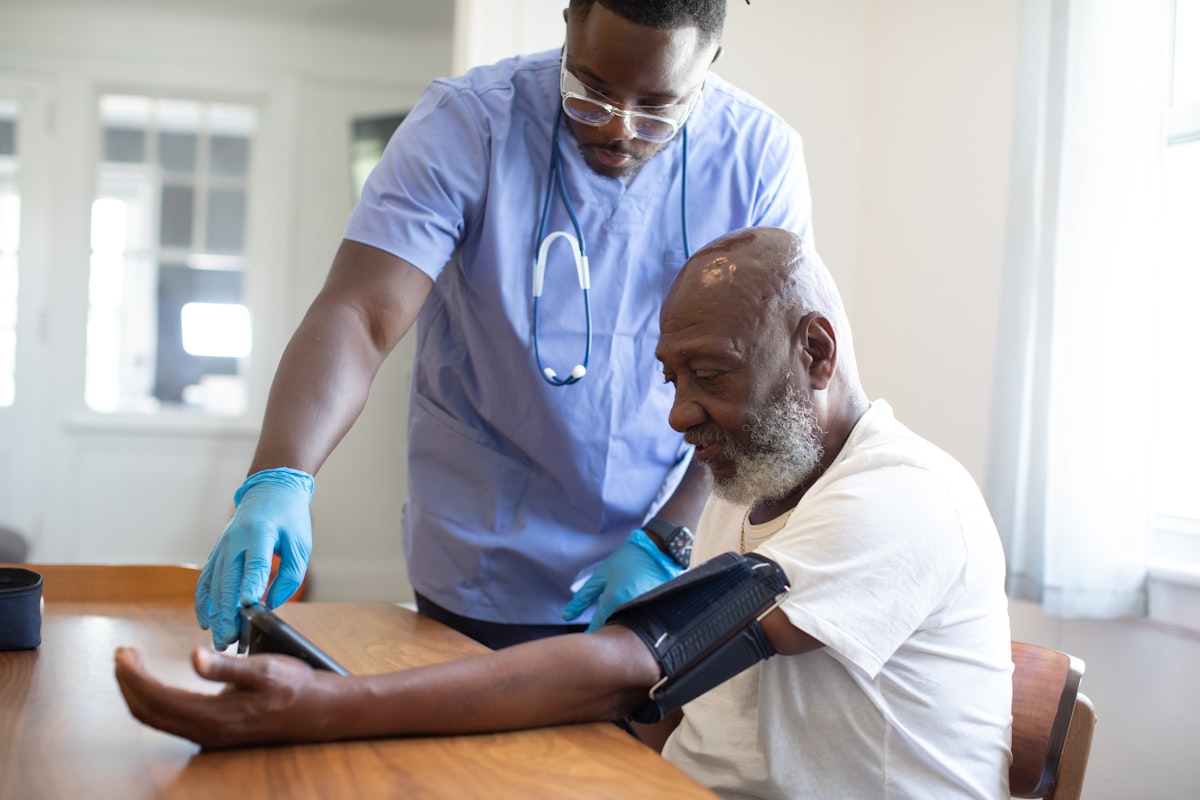 Nurse showing a patient AI charting software on a tablet during a home health visit in 2026