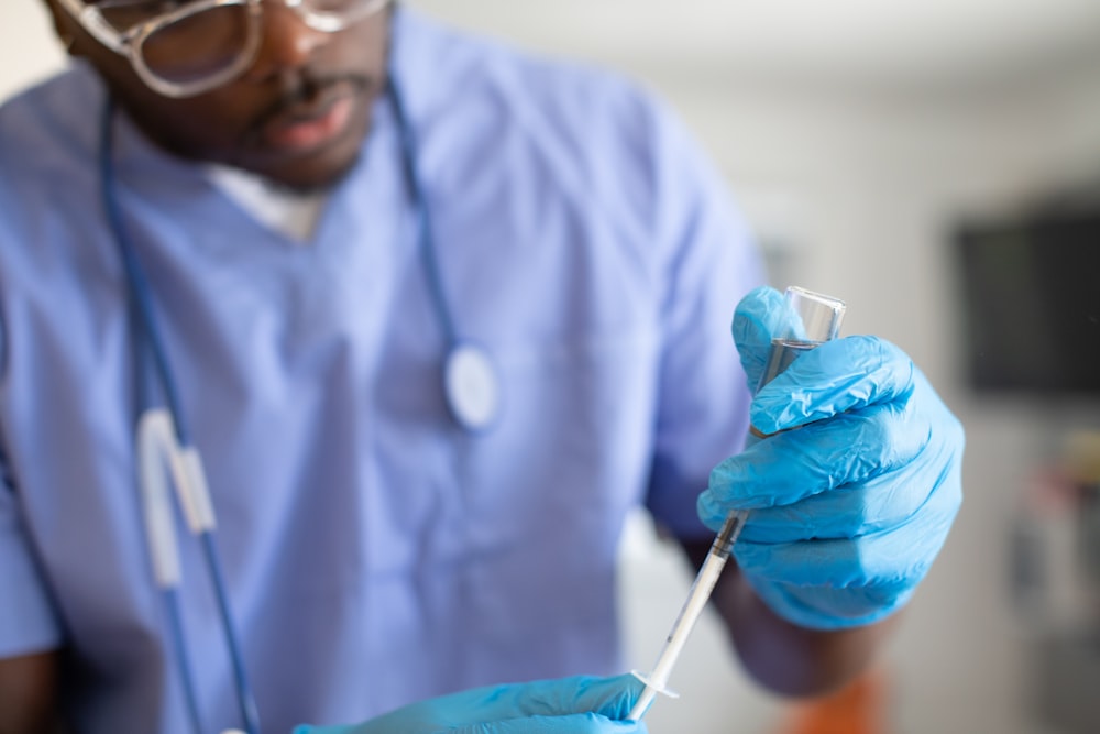 a man in a blue lab coat holding a syringe