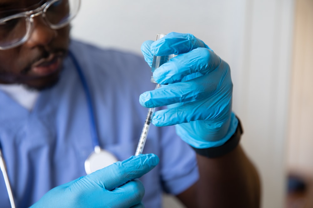 a man in a blue lab coat holding a syringe