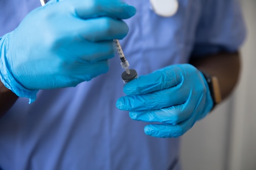 a person in a blue glove holding a syringe