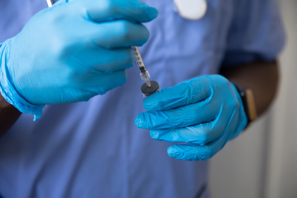 a person in a blue glove holding a syringe