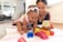A happy mother playing with her baby using colorful toys in a bright room.