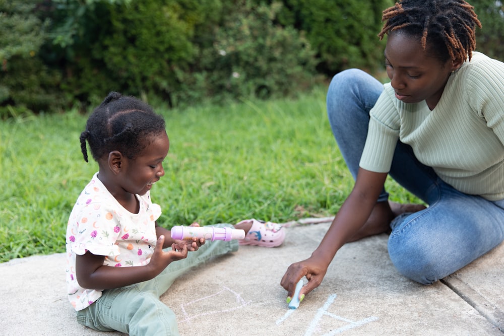 a person and a child sitting on a sidewalk