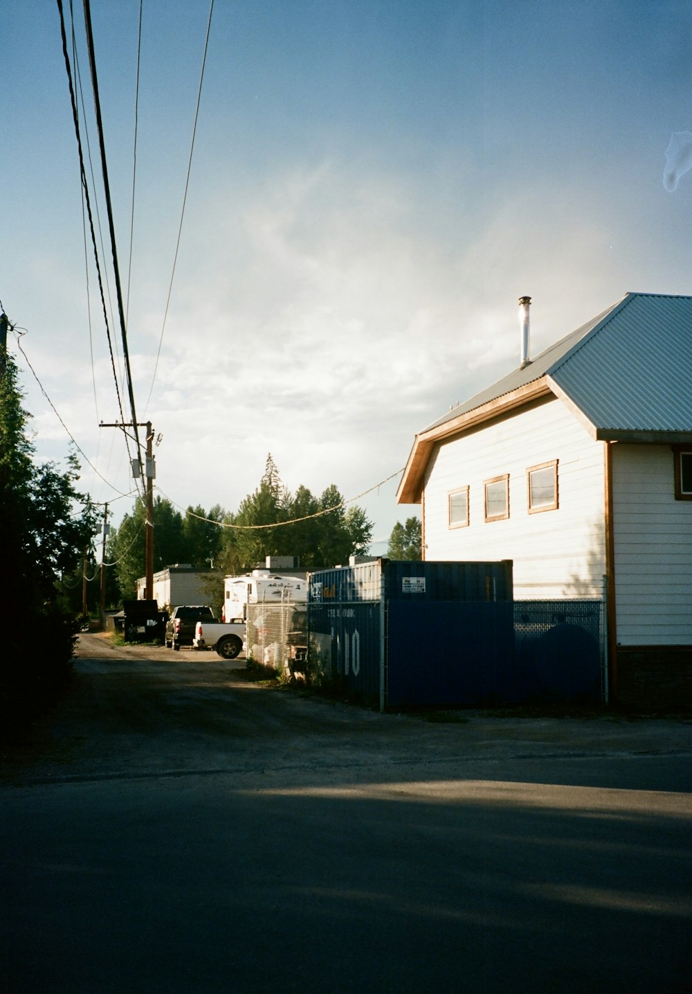 a road with a blue fence and a building with trees in the background