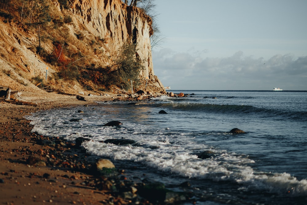 a rocky cliff next to a body of water