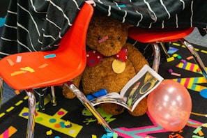The teddy bear mascot wearing a graduation cap, sitting on top of a stack of textbooks.