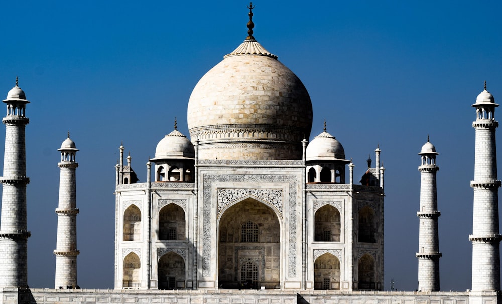 a large white building with towers with Taj Mahal in the background