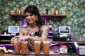 a woman holding a group of glasses of beer