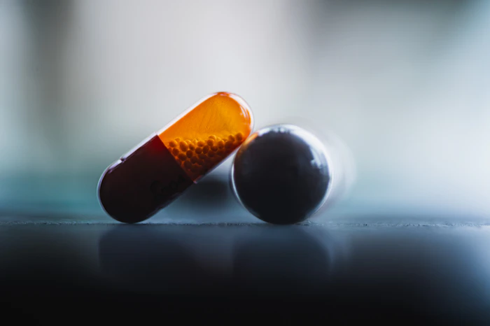 Two capsules resting on a reflective blue surface