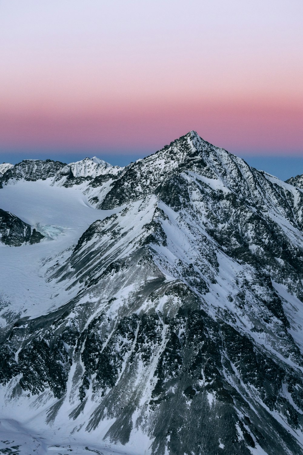 a snowy mountain with a pink sky