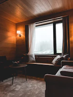 Cozy living room with rain-soaked window views and warm wooden furniture.