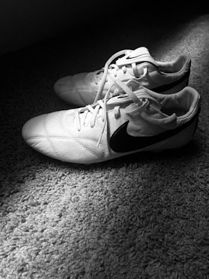 Stylish indoor soccer shoes with non-marking soles displayed on a polished gym floor.
