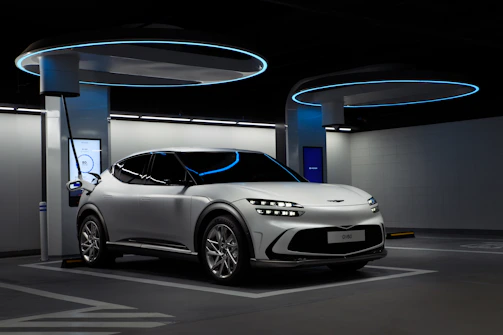 A sleek electric vehicle charging at night, illuminated by vibrant electric blue and cyber lime lights against a deep charcoal backdrop.