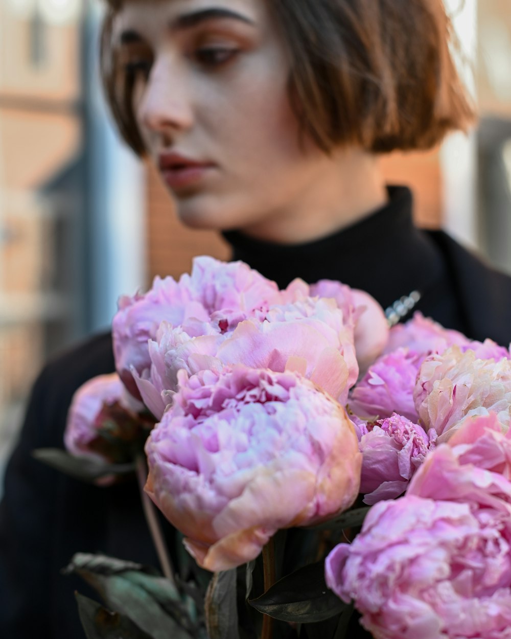 a woman holding a bouquet of pink flowers