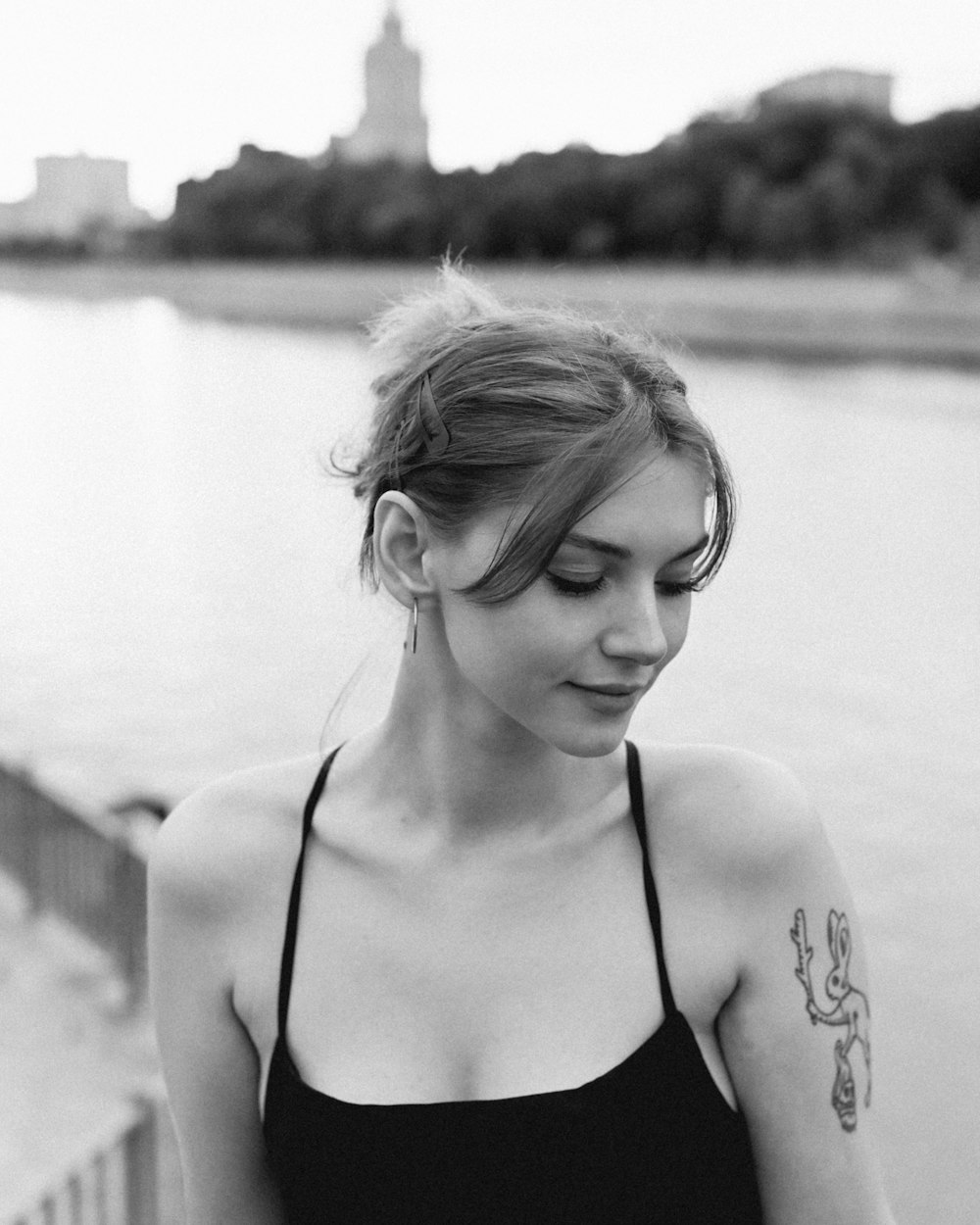 a woman with a tattoo on her arm by a body of water