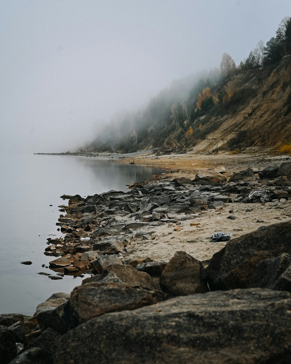 a rocky beach with a foggy sky