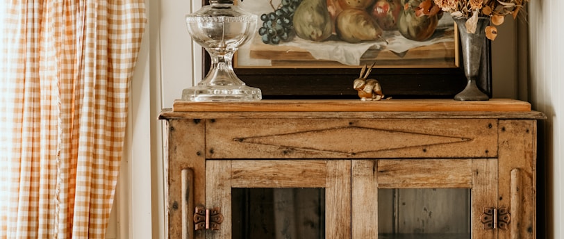 a cabinet with a vase and glass on top