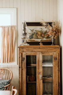 a cabinet with a vase and glass on top