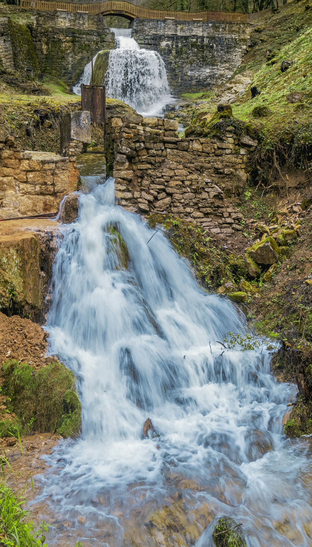 a waterfall with a stone wall