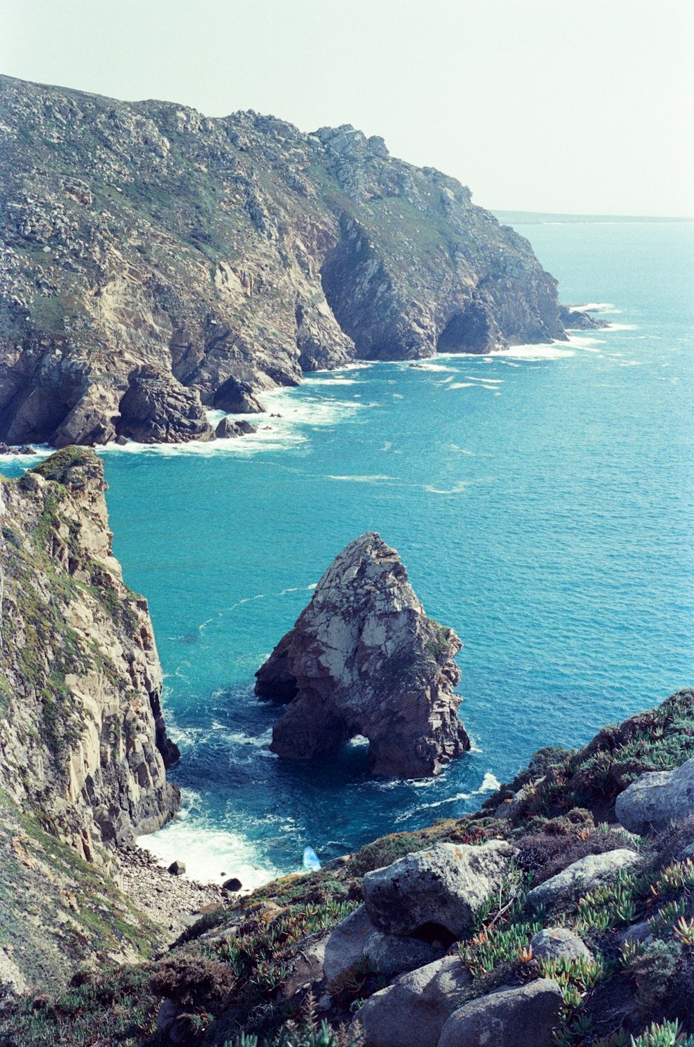 a rocky cliff next to a body of water