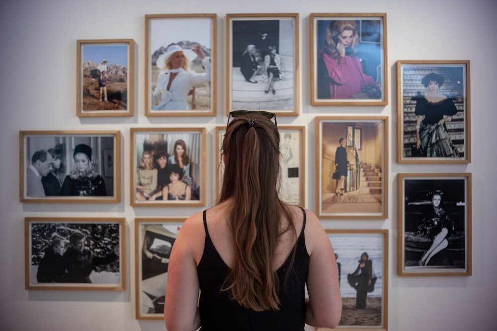 a woman looking at a wall of photos