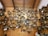 A collection of intricately designed cuckoo clocks displayed on a wooden wall. The clocks vary in size and design, featuring detailed carvings, miniature figurines, and ornate decorations. The setting appears to be a shop or exhibit dedicated to showcasing these traditional timepieces.