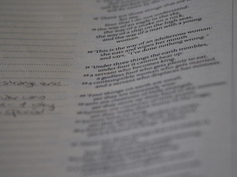 A close-up view of a page from a book with text printed in columns. The text includes numbered entries or verses and is positioned towards the right side of the image, with some handwritten notes visible on the left margin.