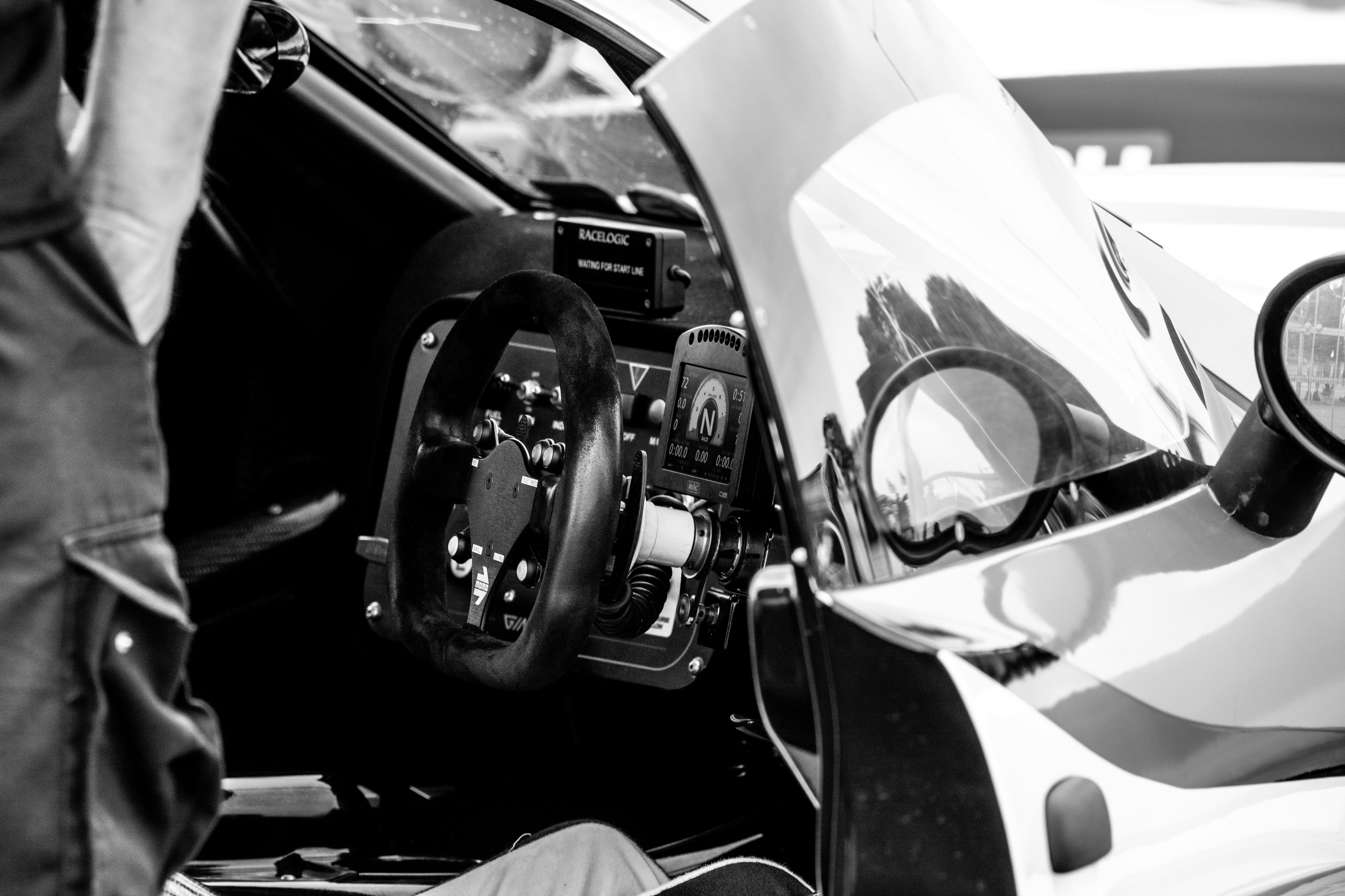 View from inside a sim racing cockpit, showing wheel, screen and track.