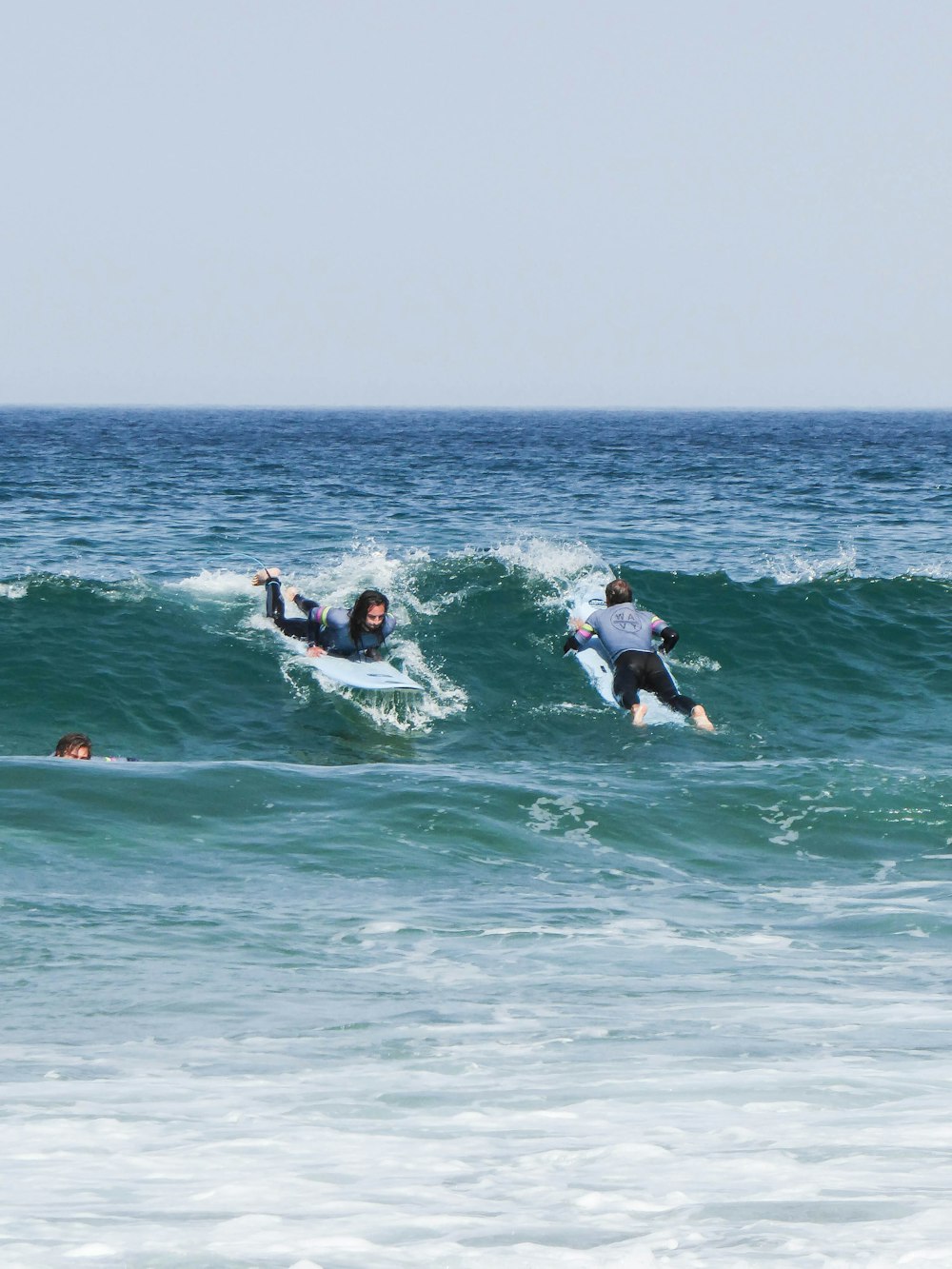 a group of surfers ride a small wave