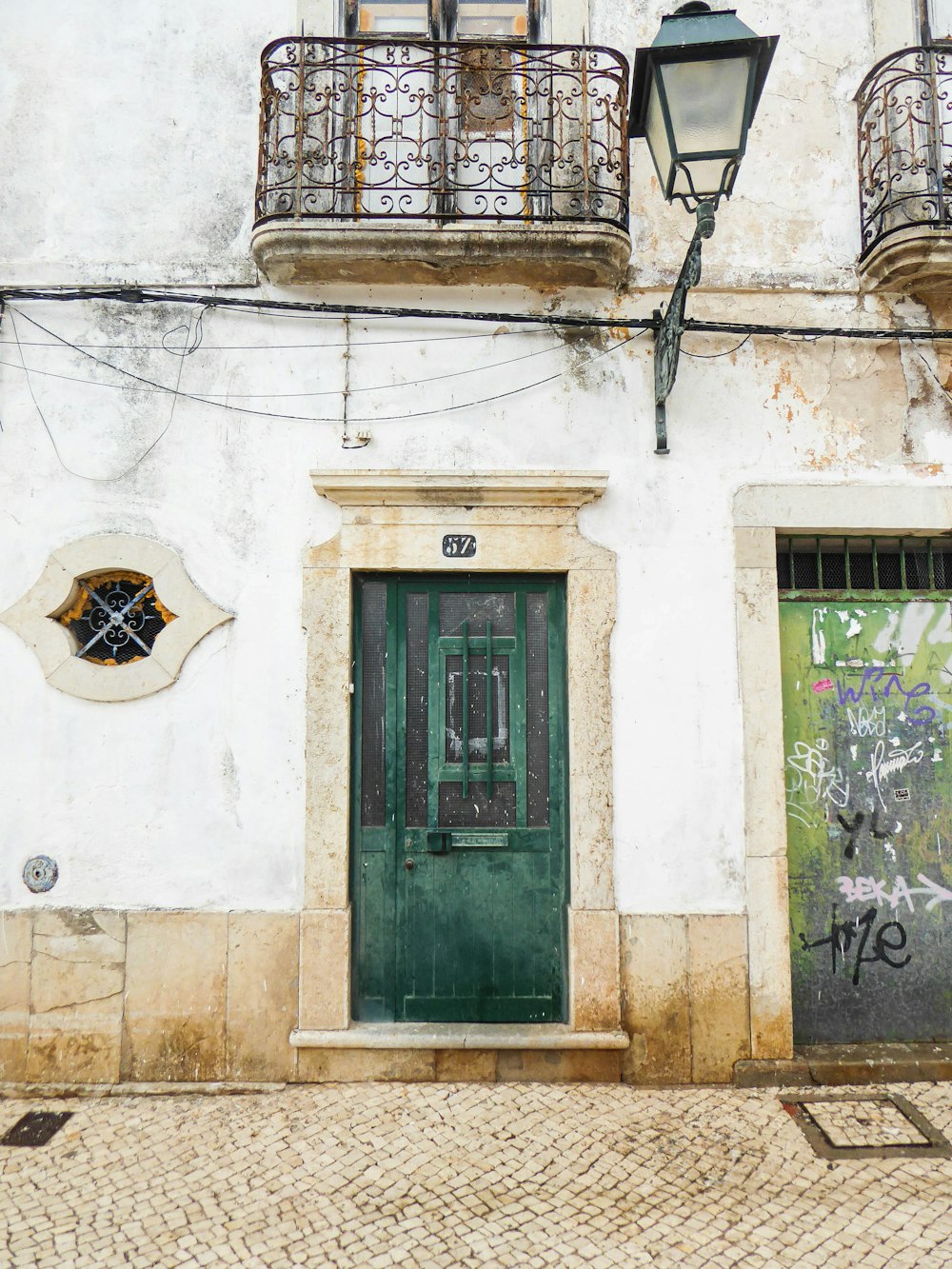 a building with a green door and a light on the side