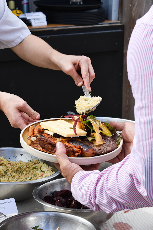A server plating food for a guest at a buffet