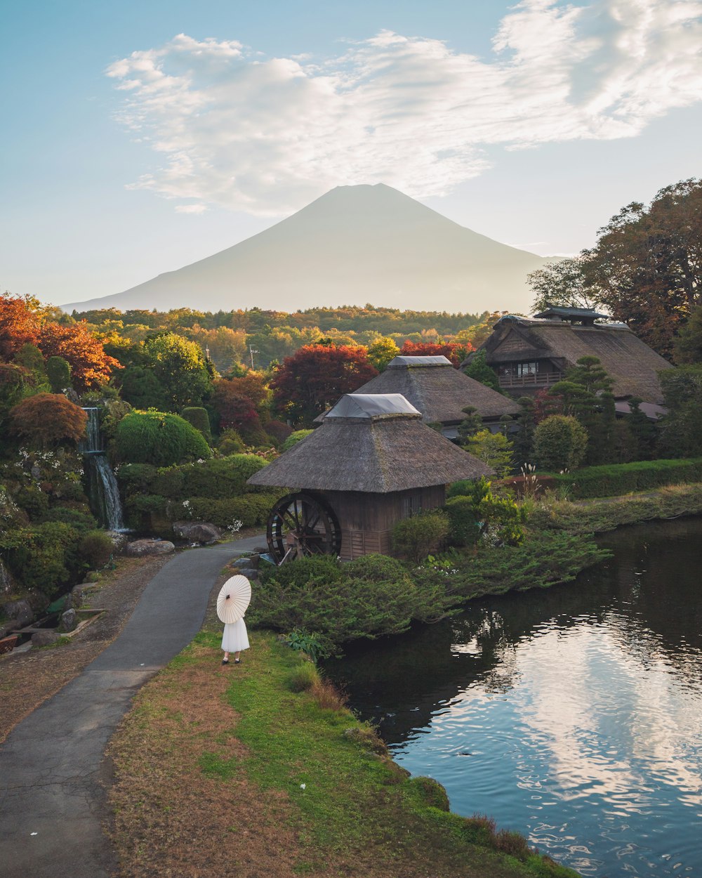 a pond with a statue in the middle of it and a mountain in the background