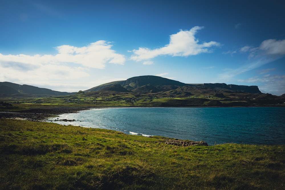 a body of water with grass and hills around it