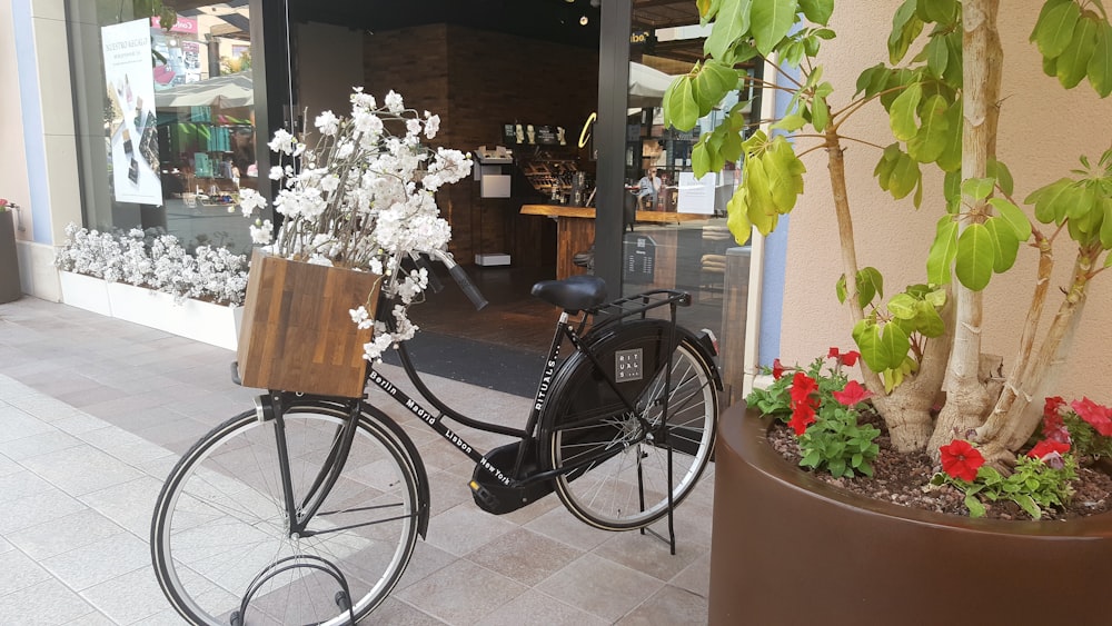 a bicycle parked next to a planter with flowers