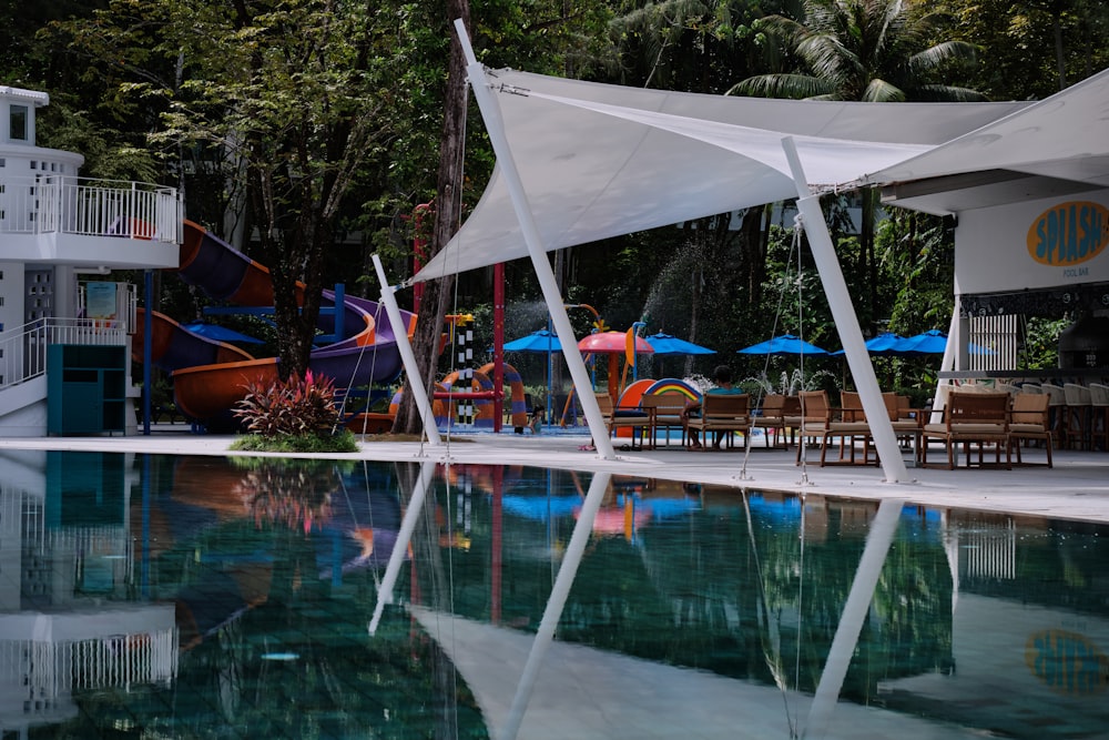 a pool with a lounge chair and umbrellas by it