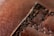 A close-up view of brown leather with detailed stitching running vertically. The texture of the leather is visible, showing its grainy surface and aged appearance.