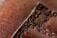 A close-up view of brown leather with detailed stitching running vertically. The texture of the leather is visible, showing its grainy surface and aged appearance.