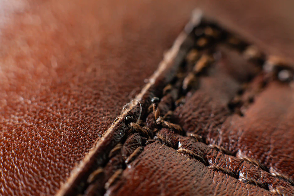 Close-up of a rich brown leather jacket draped over a vintage chair, highlighting the fine stitching and texture.